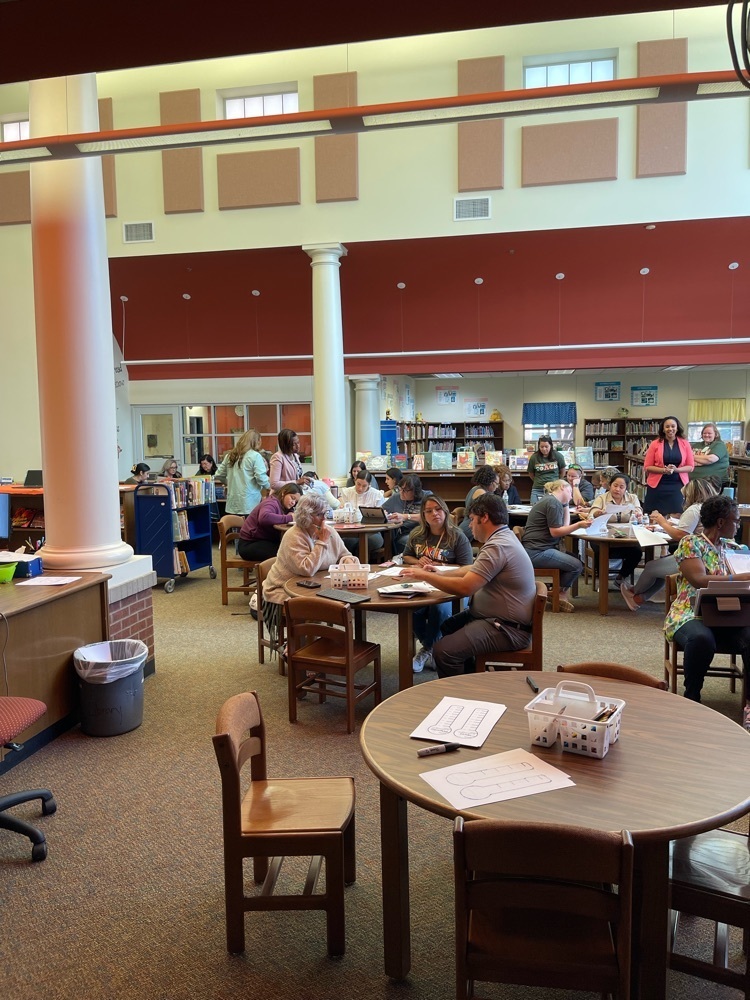 teachers sitting in the library at round tables 