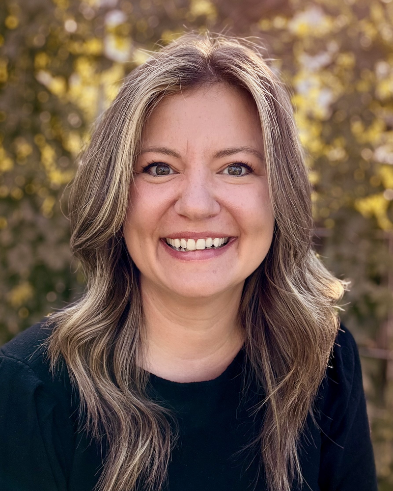 Photo of Mallory Hoffart looking at the camera with trees in the background.
