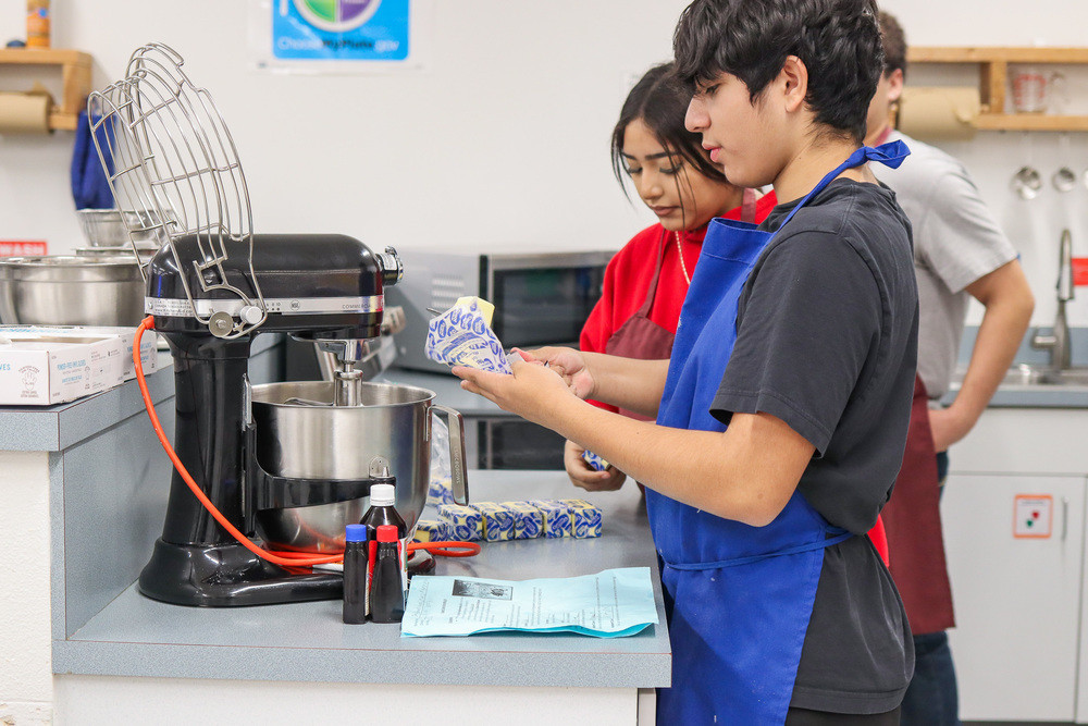 students making frosting for cookie boxes