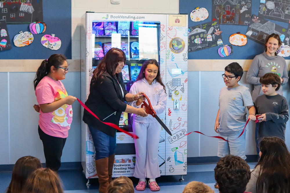 3rd grade students watch as  the ribbon is cut for the new vending machine 