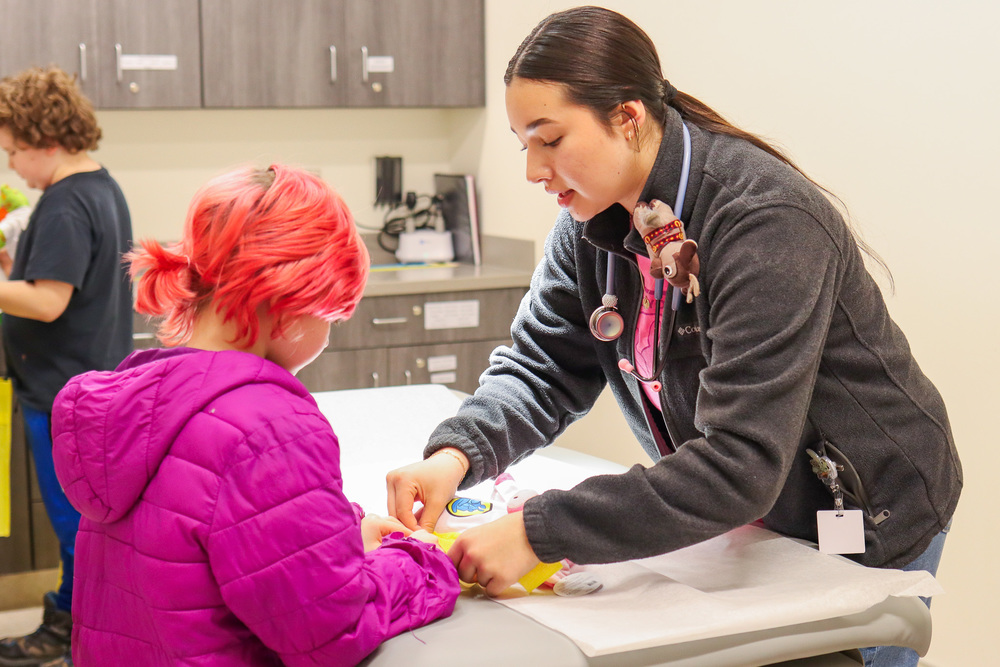 Student and nurse putting splint on teddy bear