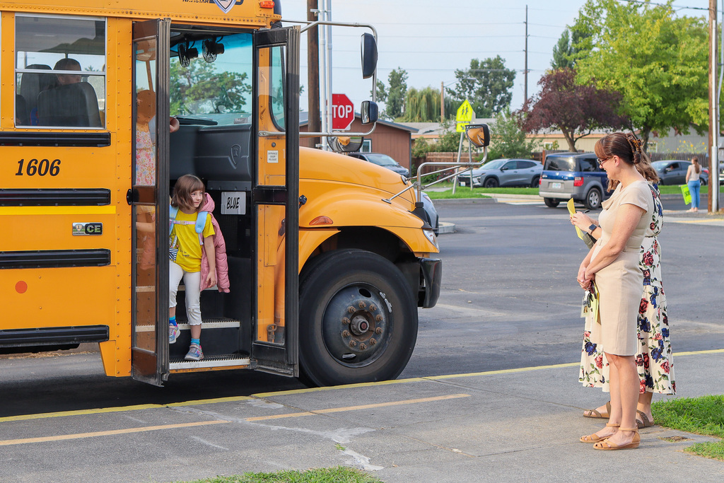 Students getting of the bus and greeted by school staff