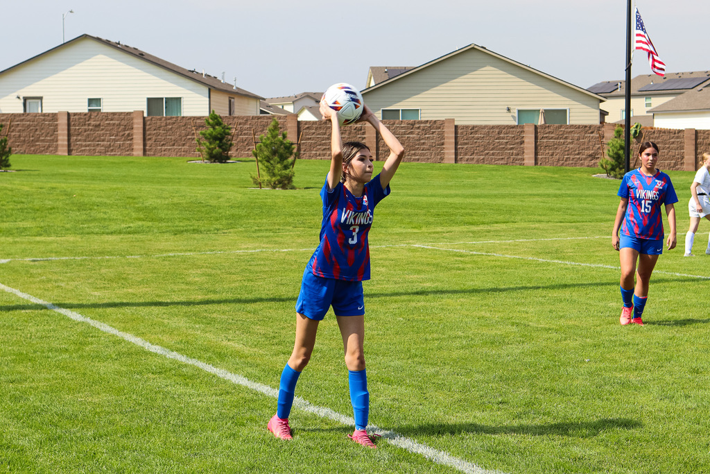 high school soccer athlete throwing ball from sidelines