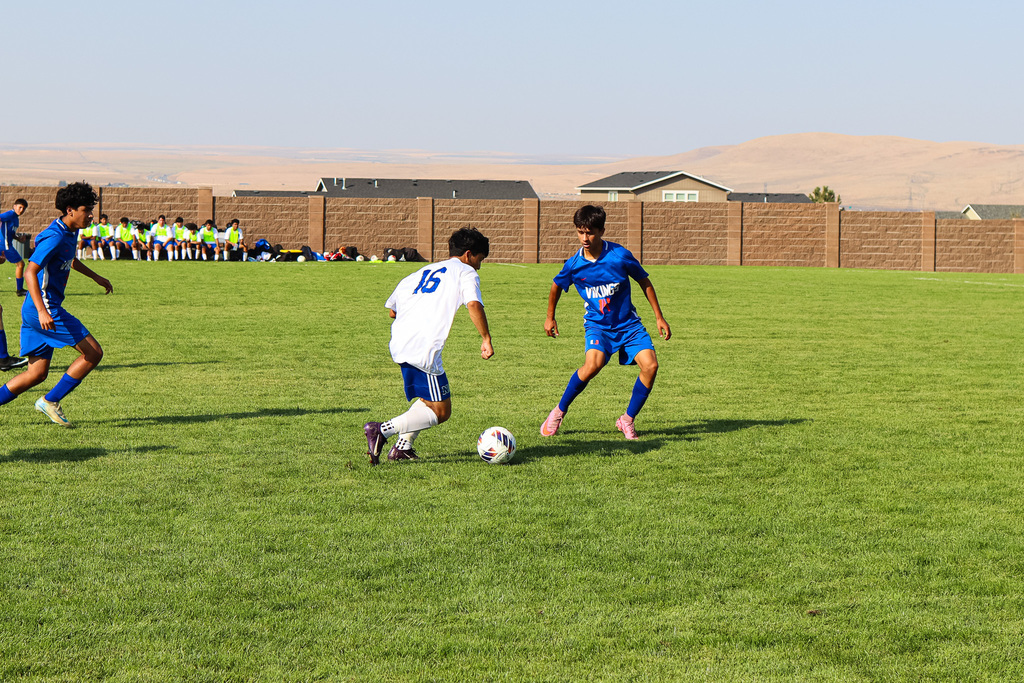 high school soccer player taking the ball away from opponent