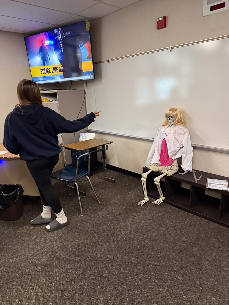 student pointing to prop at crime scene station