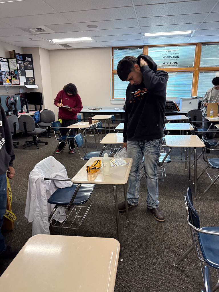 student looking for clues at crime scene station