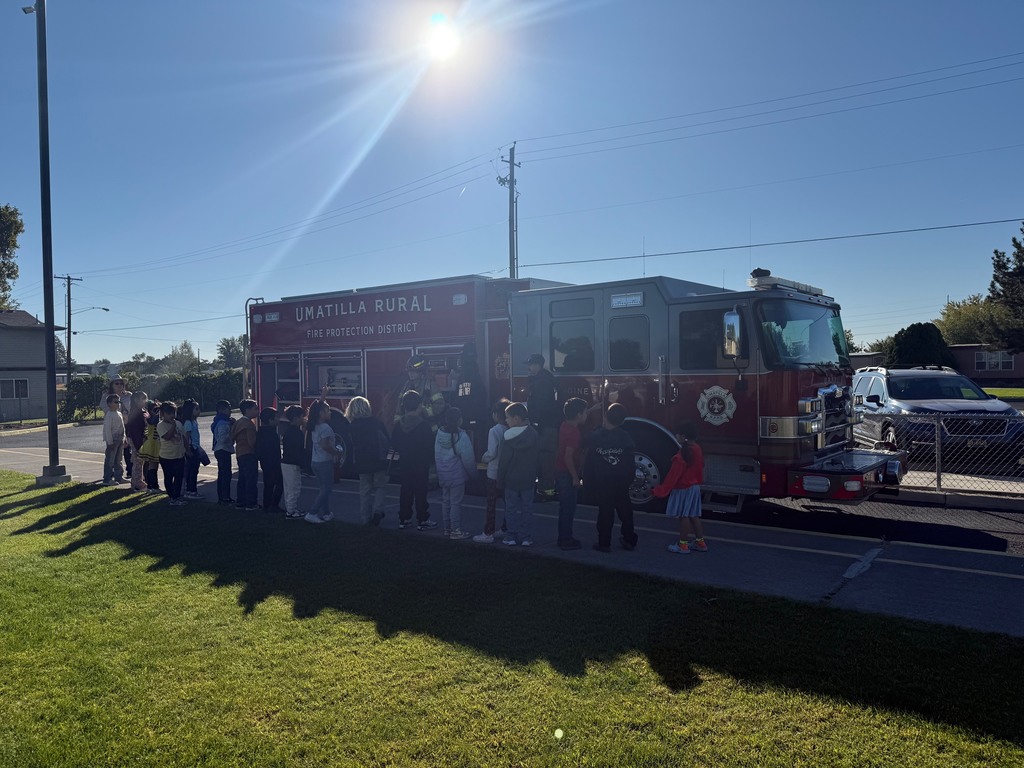 Students talking to firefighters and looking at the firefighter truck