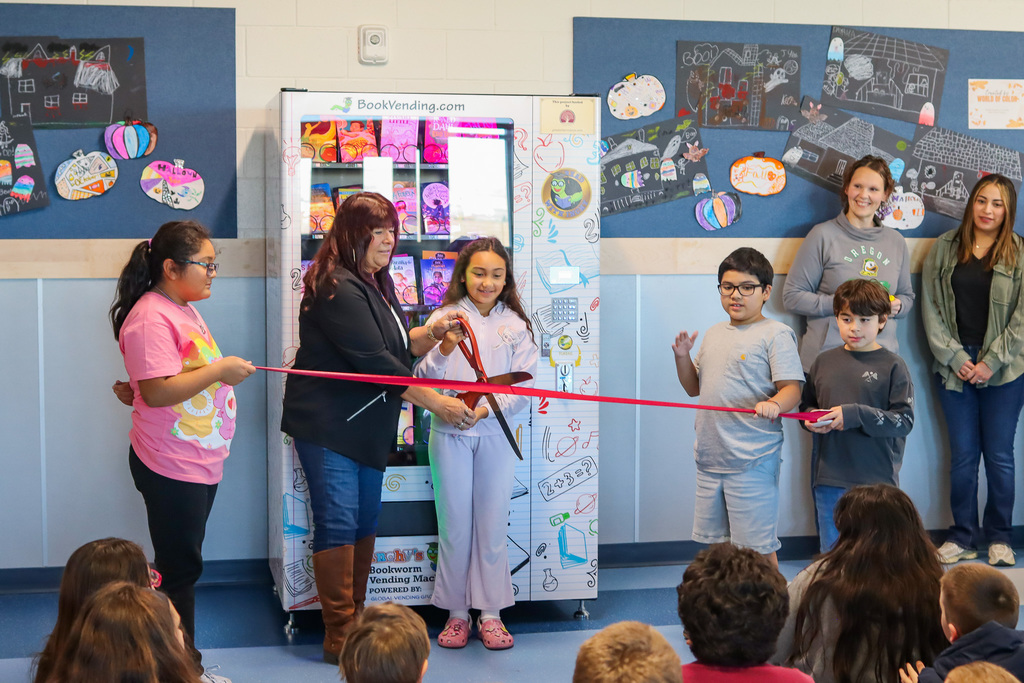 Students watching as the ribbon is cut for the new machine