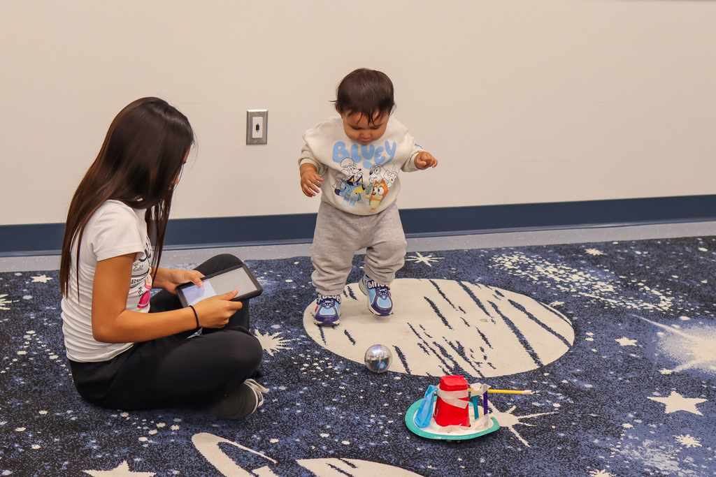 student and little sibling playing with remote controlled sphere