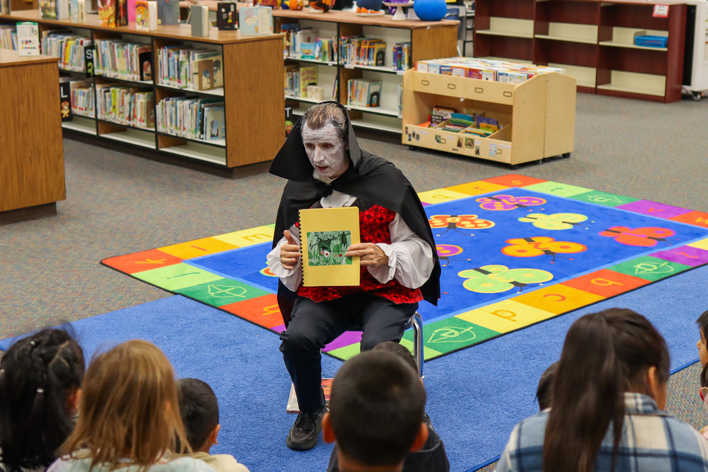 Photo of Mr. Lougee dressed as a vampire holding up a book 