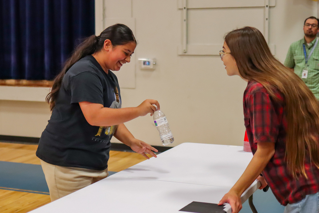 student playing flip the water bottle game in assembly