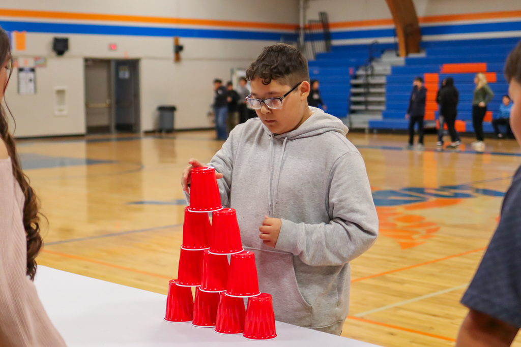 student playing the cup stacking game in assembly 