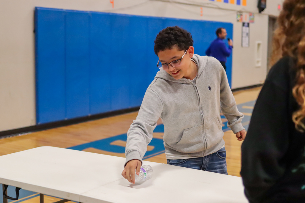 student playing flip the water bottle game in assembly