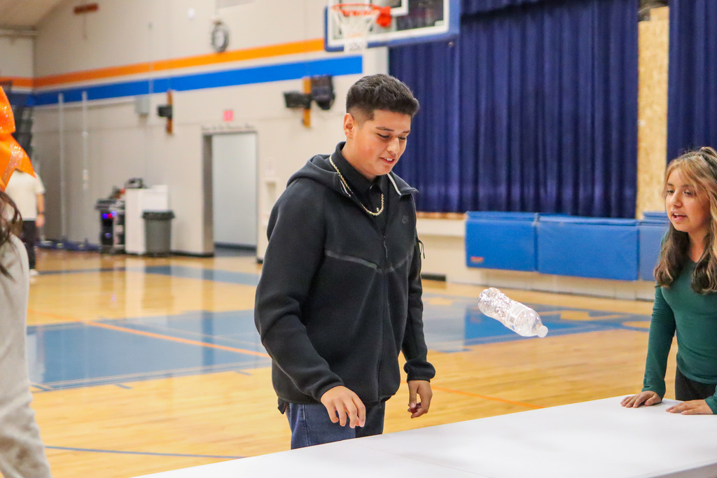 student playing flip the water bottle game in assembly