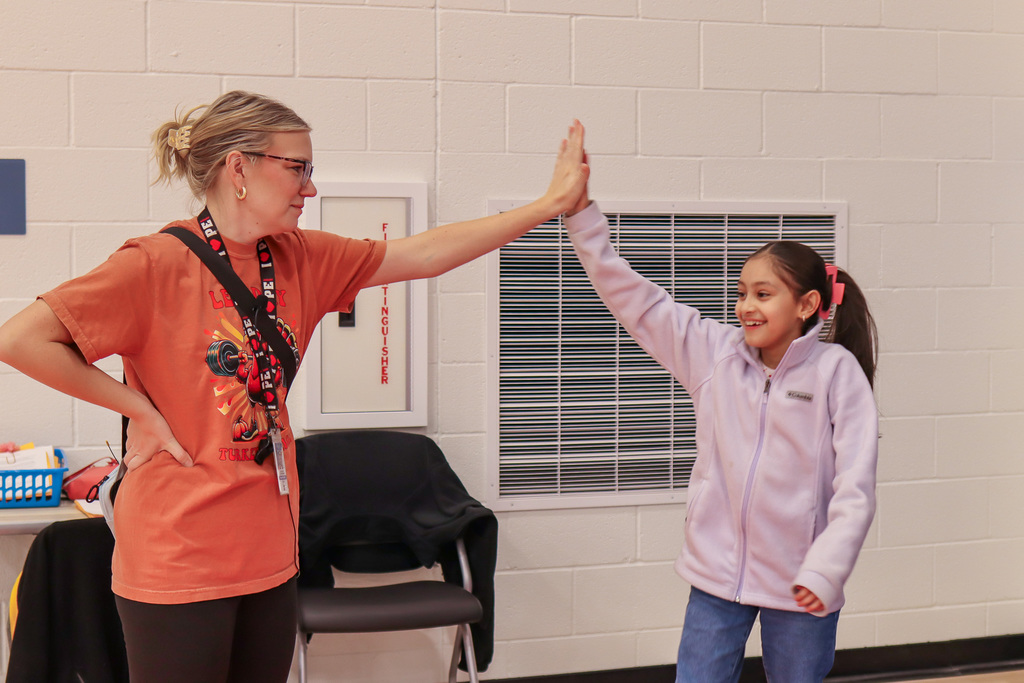 Mrs. Hernandez high-fiving student for completing the rock wall 