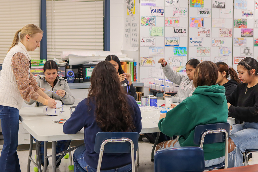 Students tying ribbon around cookie boxes 
