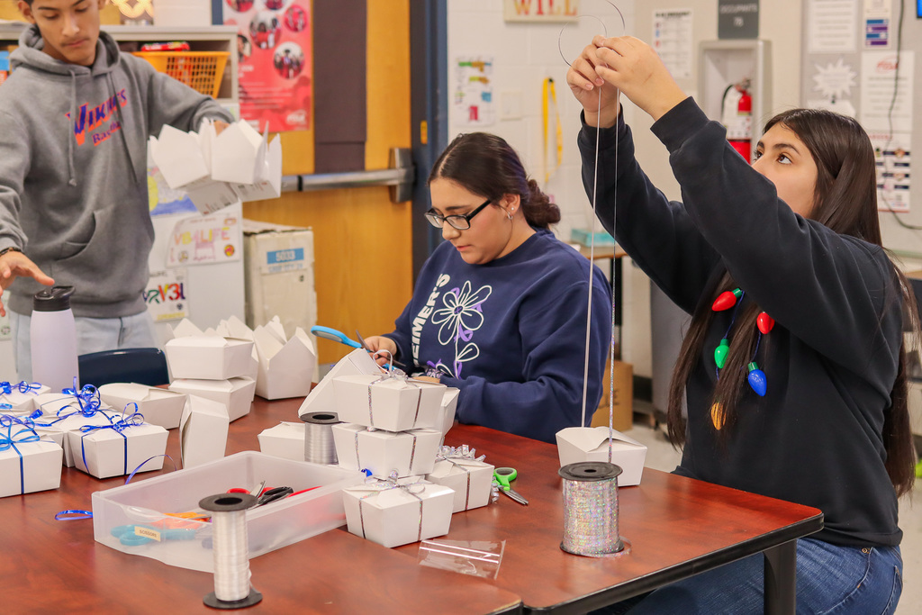 Students tying ribbon around cookie boxes 