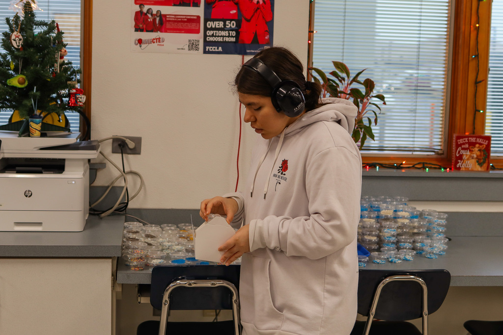 student filling cookie boxes with sprinkles 