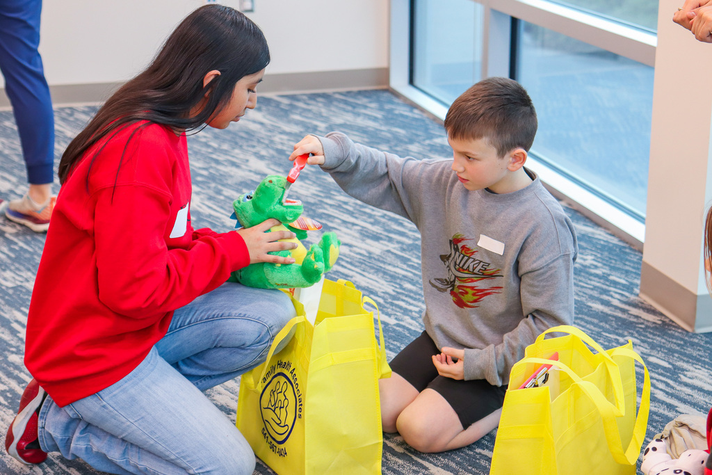 student brushing teeth on stuffed animal with help of student nurse