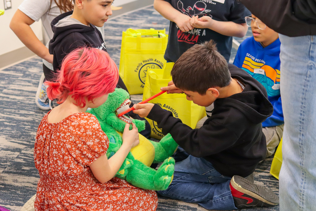 student brushing teeth on stuffed animal
