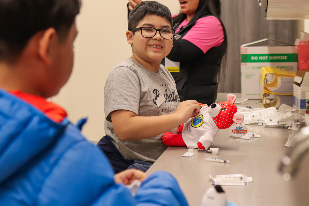student putting a band aid on their teddy bear buddy 