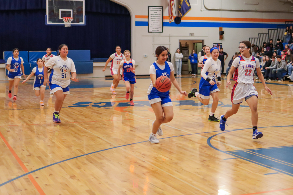 Player dribbling the ball down the court while other players follow behind
