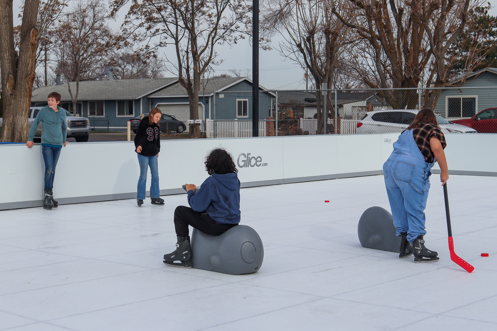 students skating on the rink and also playing hockey