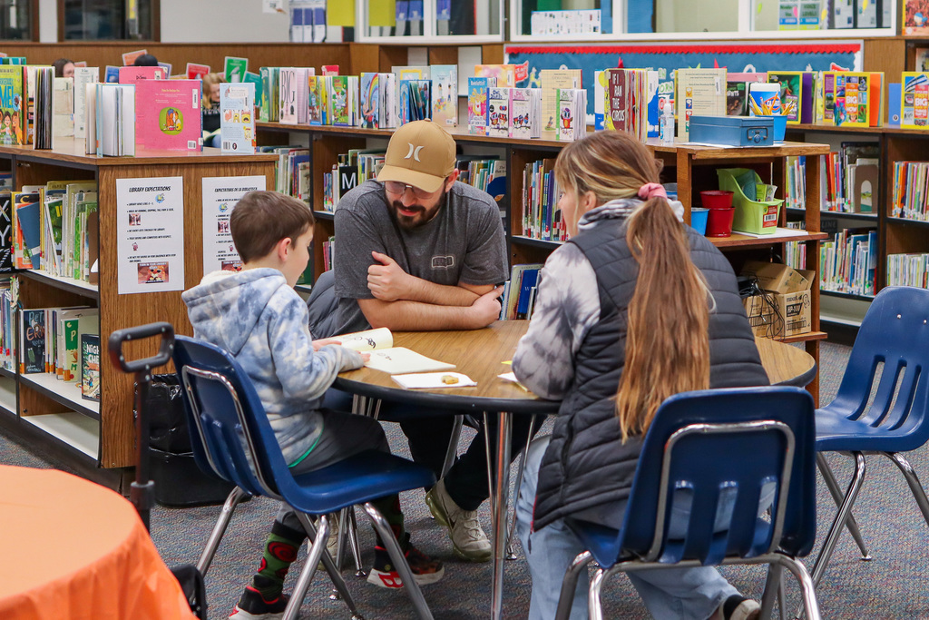 Student reading book to family