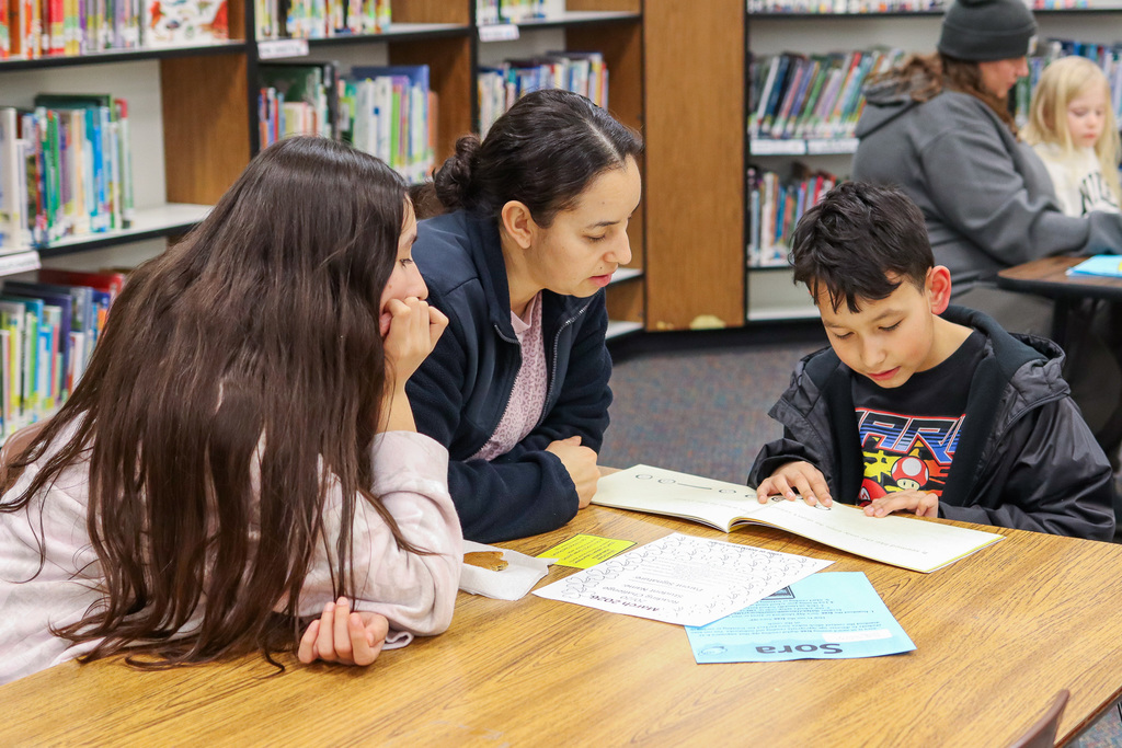 student reading book to family members 