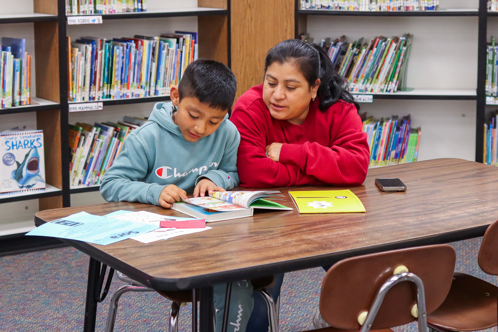 A student reading a book to their family