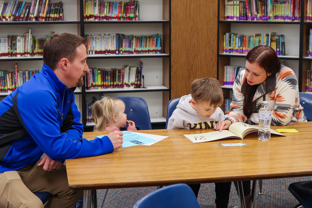 Student reading book to family