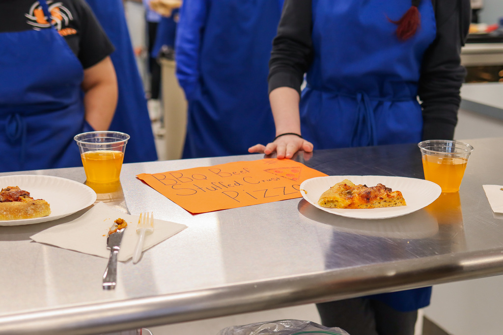 Photo of sliced pizzas and sign made by students 