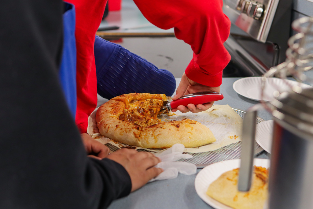 student cutting slices of pizza 