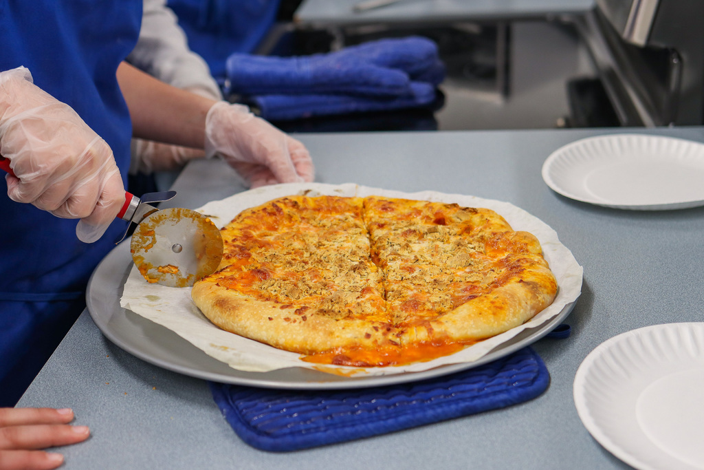 student cutting a slice of pizza 
