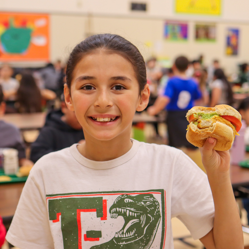 student holding up their chicken burger showing all the toppings added 