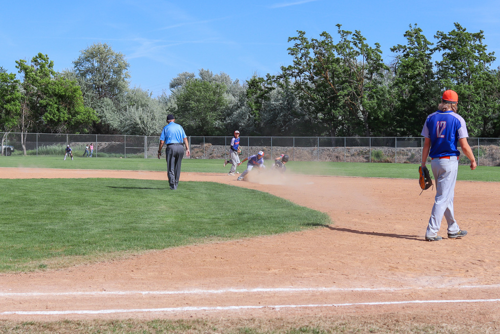 UHS baseball player catches the ball as an opposing runner slides into second base