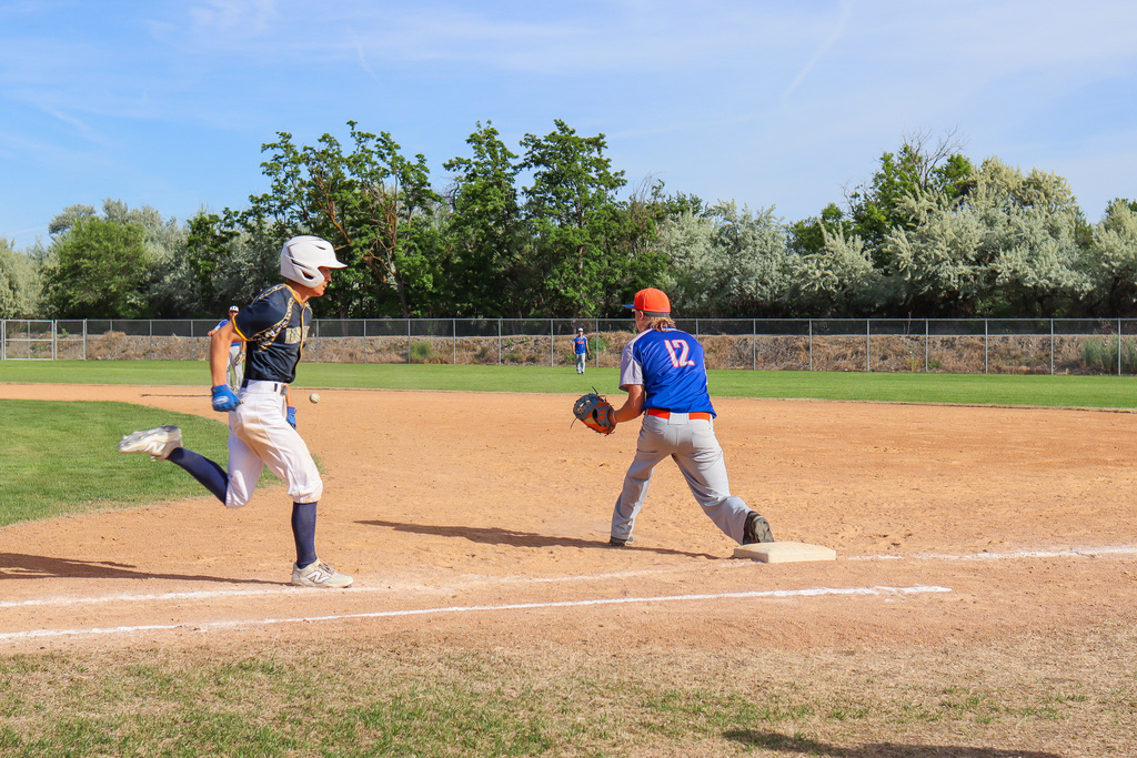 opponent running to 1st base while senior #12 prepares to catch ball 