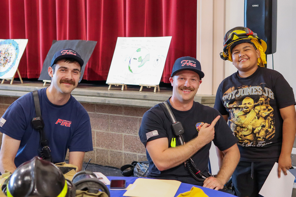 Firefighters pictured with student wearing firefighter hat 