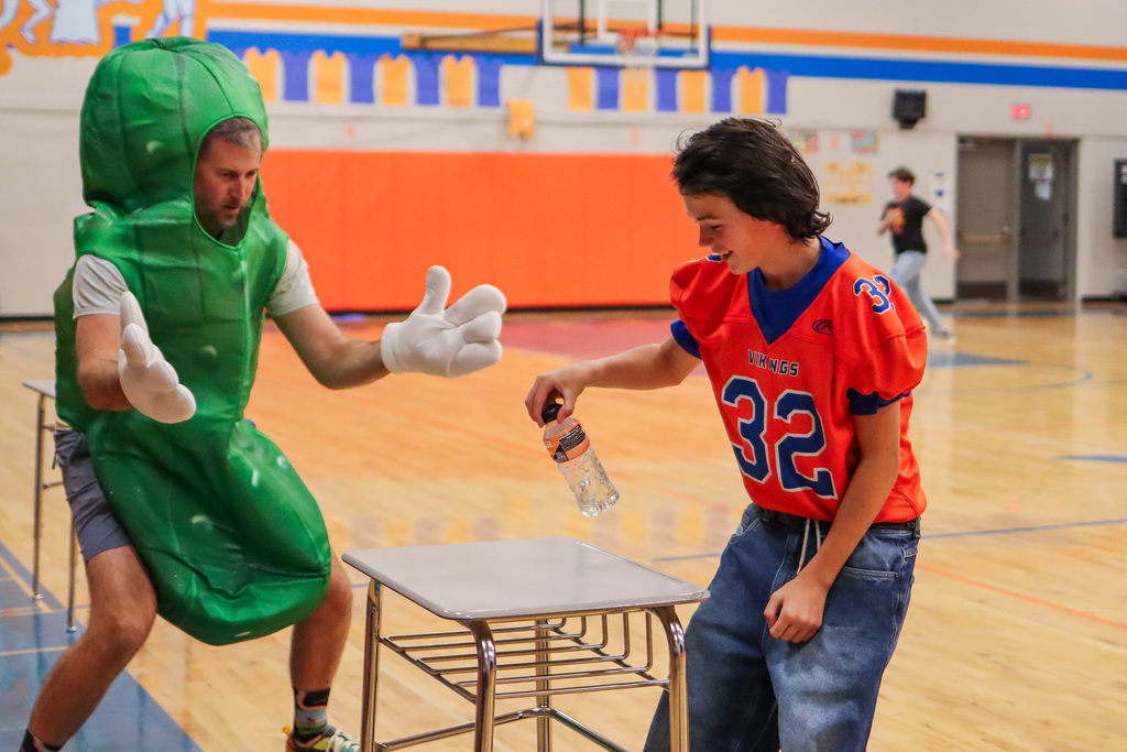 Student playing flip the water bottle game during CBMS Homecoming Assembly