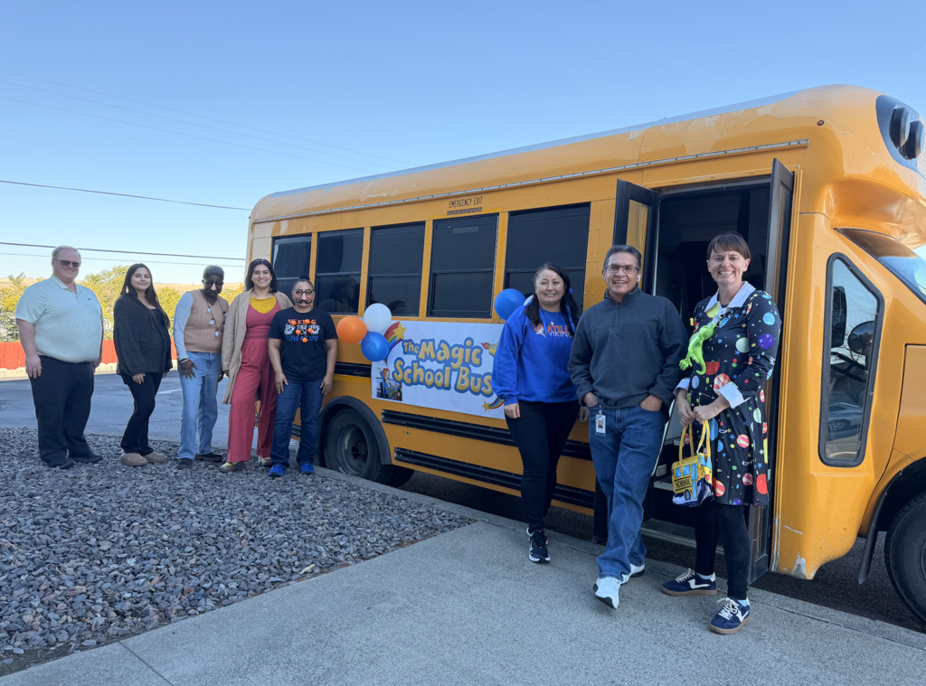 Photo of district staff standing in front of a school bus dressed as characters from the show the Magic School Bus