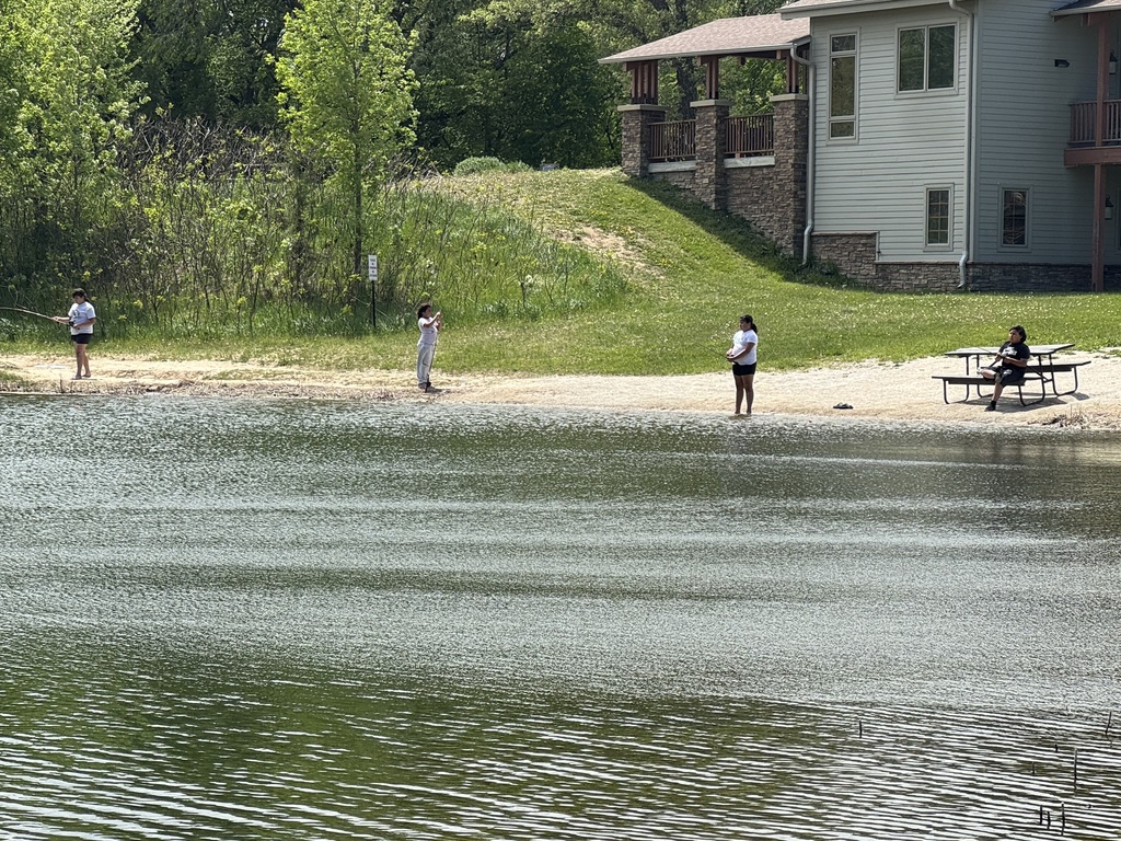 Wide view of the lake with students fishing and enjoying the day