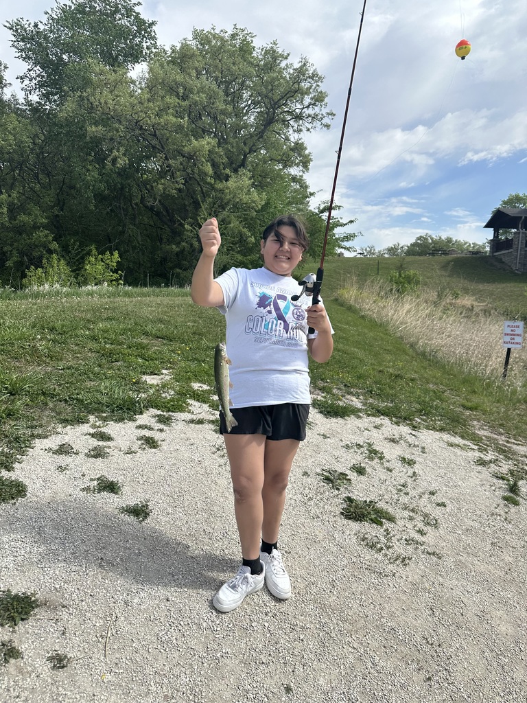 Student holding their catch in one hand and a fishing rod in the other