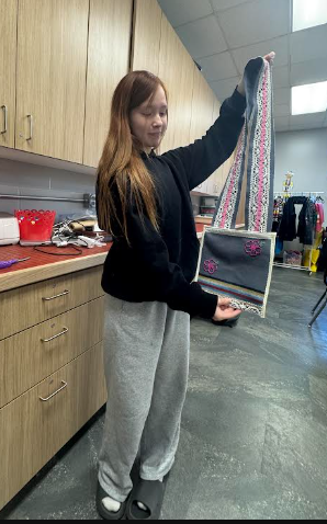 Student holds a black and red crossbody bag.