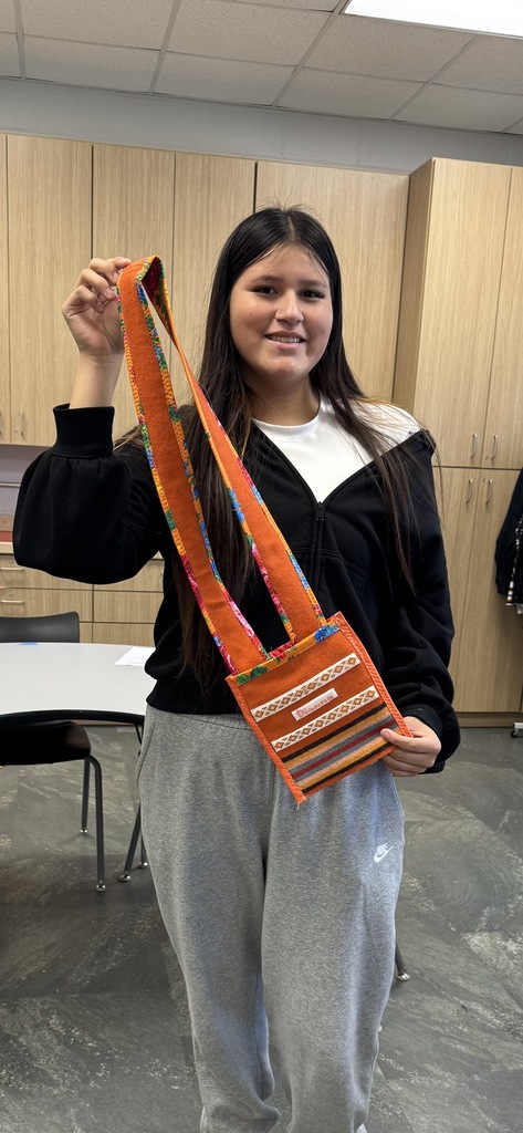 Student holds orange, colorful cross-body bag