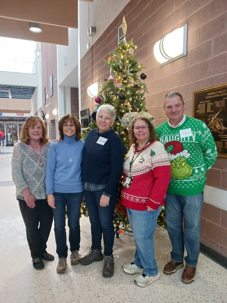 Five people stand in front of christmas tree