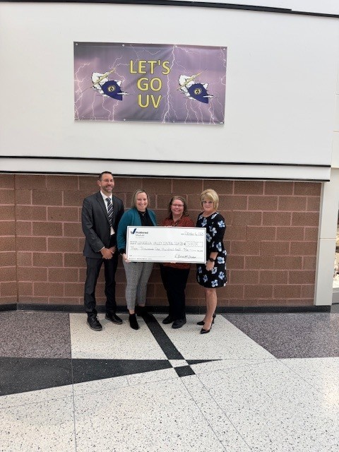 Four people hold a check