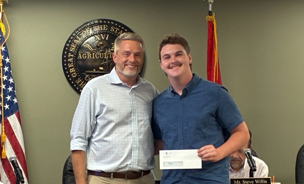 Director of schools standing next to student holding an envelope.