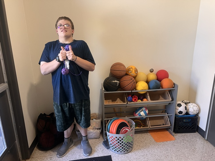 Kyle next to a newly organized shelf of outdoor toys