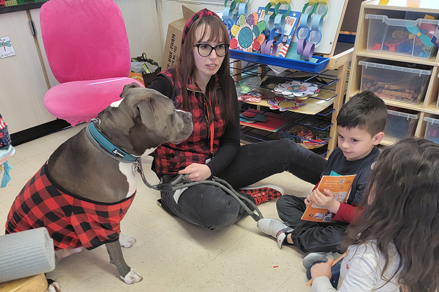 adult and therapy dogs sit around with children in a circle