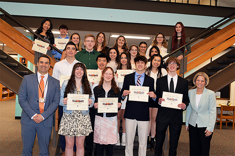 students standing in front of a staircase with certificates